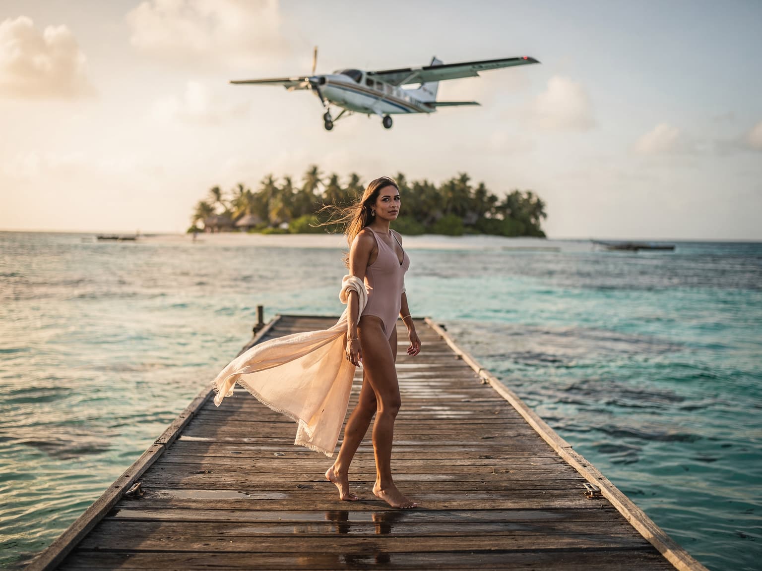Una mujer en el muelle de San Andrés con el mar de los siete colores detrás y una avioneta sobrevolando